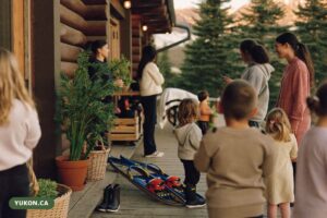 Log-built early learning centre among spruce trees in the Yukon with small boots on the porch