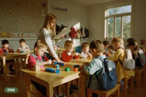 Kindergarten-age children building with blocks while an educator helps in a bright classroom