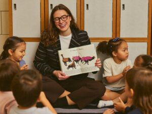 An early childhood educator reading a picture book to a small circle of preschoolers