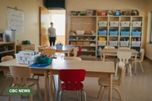 A tidy, fully prepared but empty toddler room in a child care centre, with tables and chairs ready but no children present.